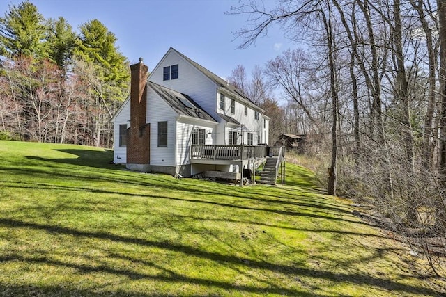 rear view of property with a lawn, a wooden deck, stairs, and a chimney