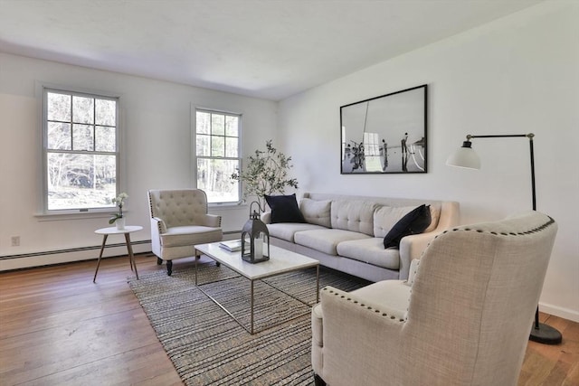 living room featuring baseboards, a baseboard heating unit, and wood finished floors