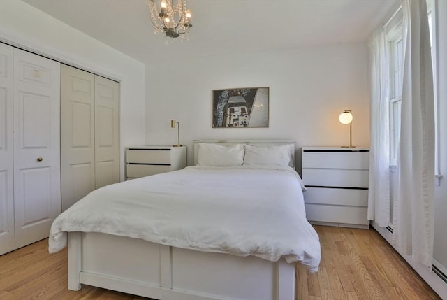 bedroom with light wood-type flooring, a chandelier, and a closet