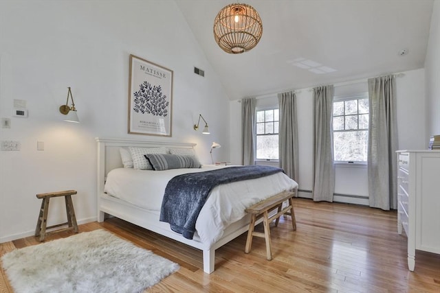 bedroom with visible vents, baseboard heating, high vaulted ceiling, light wood finished floors, and a notable chandelier