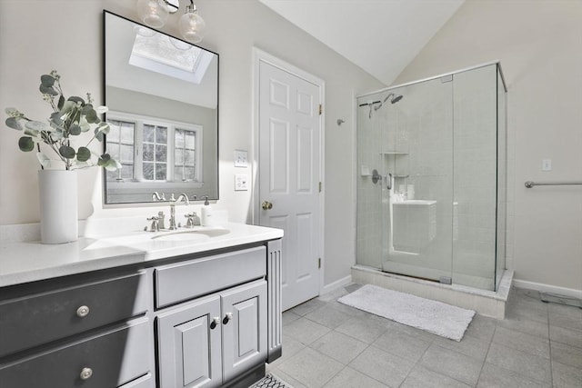 full bath featuring vanity, tile patterned floors, a stall shower, and vaulted ceiling with skylight