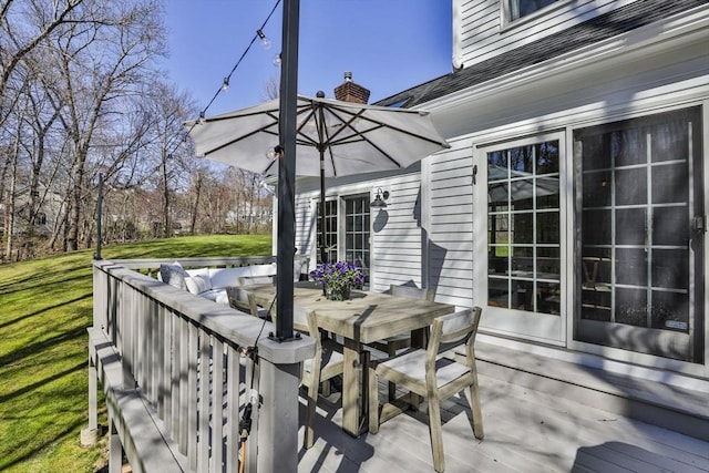 deck featuring outdoor dining space and a yard
