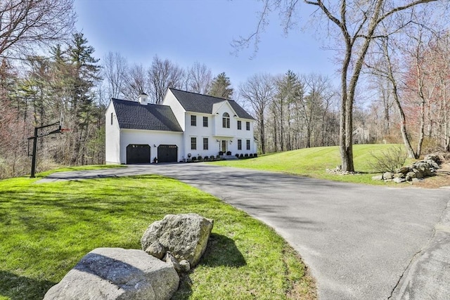 view of front of property with roof with shingles, an attached garage, a front lawn, and aphalt driveway