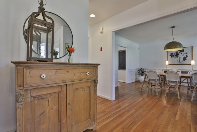 interior space featuring baseboards, brown cabinetry, hardwood / wood-style floors, and decorative light fixtures