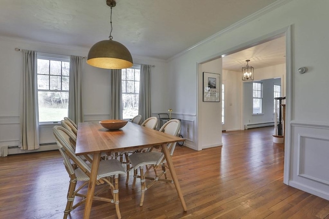 dining space with plenty of natural light, a chandelier, baseboard heating, and wood finished floors