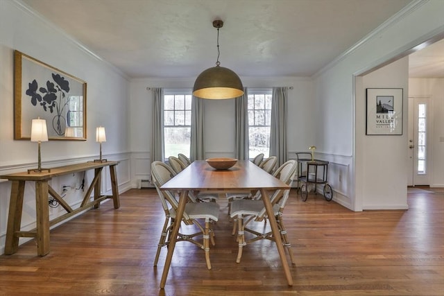 dining room featuring ornamental molding, a baseboard heating unit, wood finished floors, and wainscoting