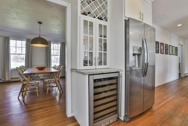 interior space featuring stainless steel fridge, white cabinetry, beverage cooler, and wood finished floors
