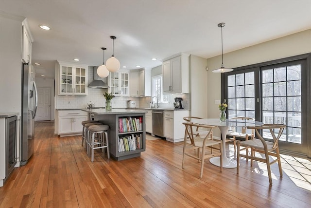 kitchen featuring light wood-style floors, glass insert cabinets, backsplash, appliances with stainless steel finishes, and wine cooler