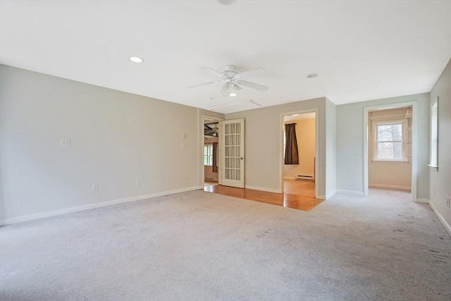 spare room with plenty of natural light, a ceiling fan, a baseboard heating unit, and light carpet