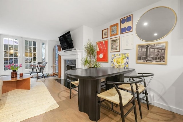 dining room featuring baseboards, wood finished floors, and a high end fireplace