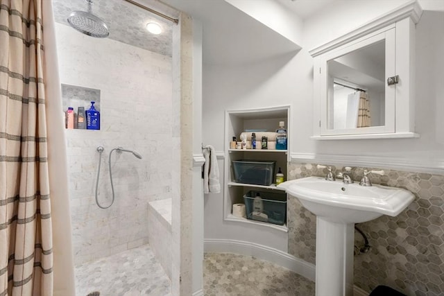 full bathroom featuring a tile shower and a sink