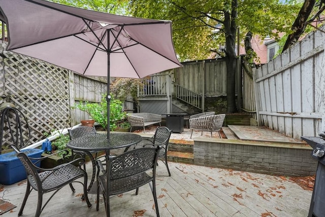 view of patio / terrace featuring a fenced backyard, a wooden deck, and outdoor dining space