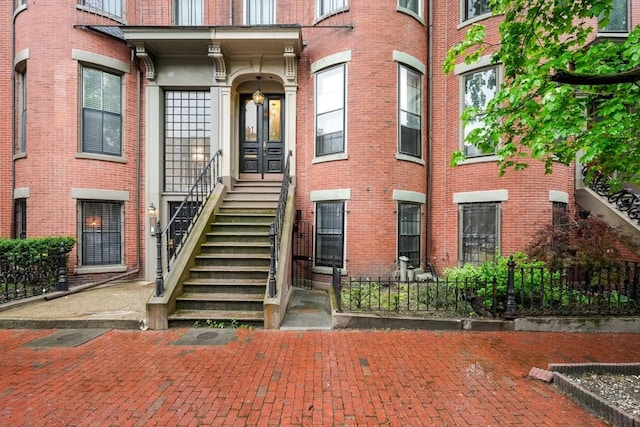 property entrance featuring brick siding and fence