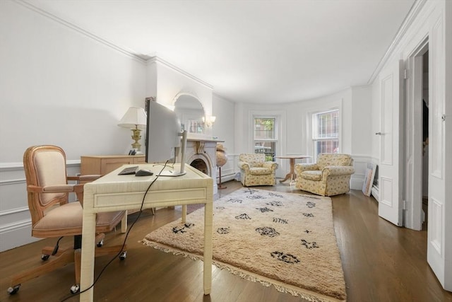 office area with ornamental molding, wood finished floors, a decorative wall, a wainscoted wall, and baseboard heating
