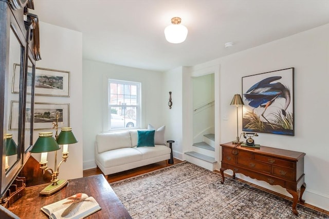 sitting room featuring stairs, baseboards, and wood finished floors