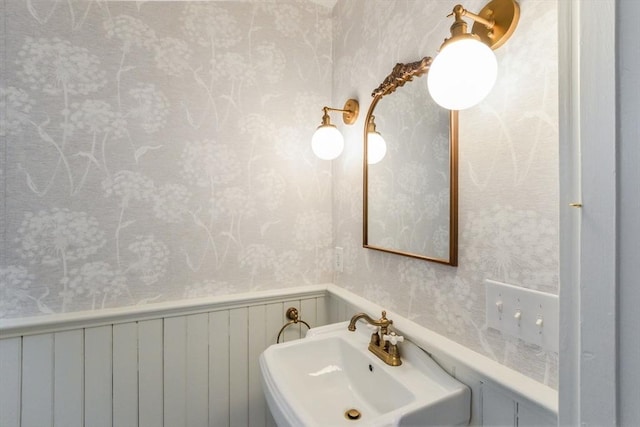 bathroom featuring a sink, radiator heating unit, wainscoting, and wallpapered walls