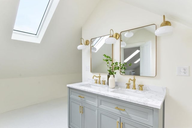 bathroom with lofted ceiling with skylight, double vanity, and a sink