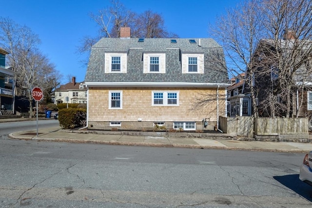 rear view of house featuring a chimney, a gambrel roof, and a shingled roof