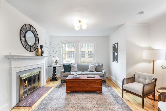 living room featuring baseboards, a glass covered fireplace, and hardwood / wood-style flooring