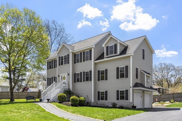 colonial house featuring fence, a garage, driveway, and a front yard