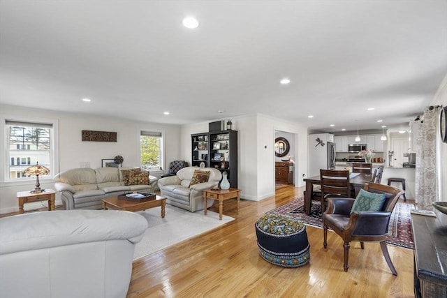 living room featuring recessed lighting, baseboards, and light wood-style flooring