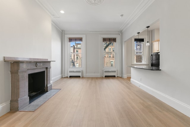 unfurnished living room with light hardwood / wood-style flooring, radiator, and a healthy amount of sunlight