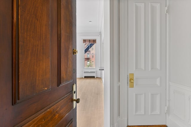 hallway with radiator heating unit and light hardwood / wood-style flooring