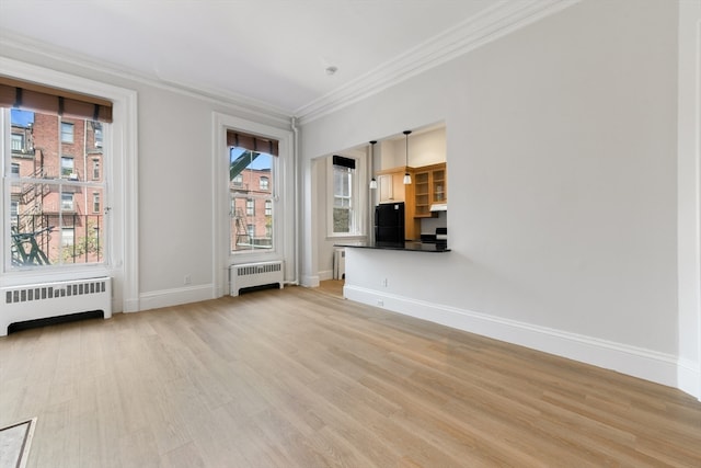 empty room featuring light hardwood / wood-style flooring, radiator, and ornamental molding