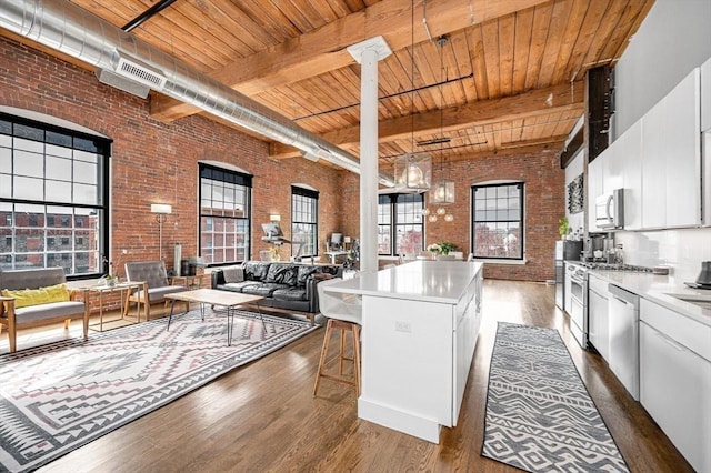 kitchen featuring brick wall, stainless steel appliances, wooden ceiling, dark wood-type flooring, and a kitchen island