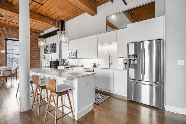 kitchen featuring a sink, a towering ceiling, wooden ceiling, and stainless steel appliances