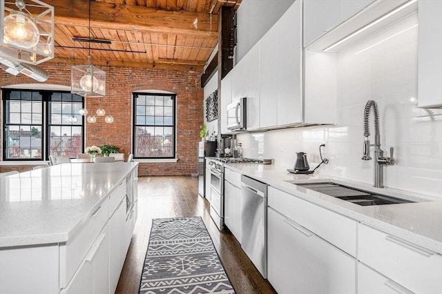 kitchen with dark wood-style flooring, brick wall, a sink, wooden ceiling, and stainless steel appliances