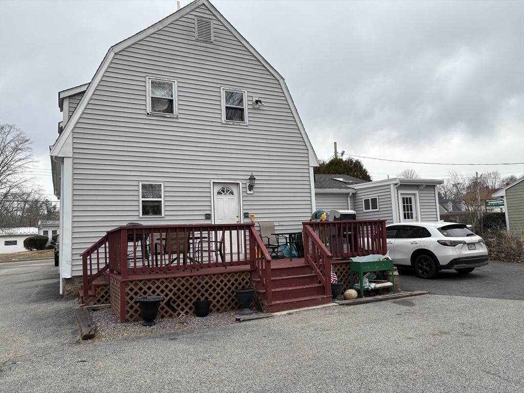 rear view of house with a deck and a gambrel roof