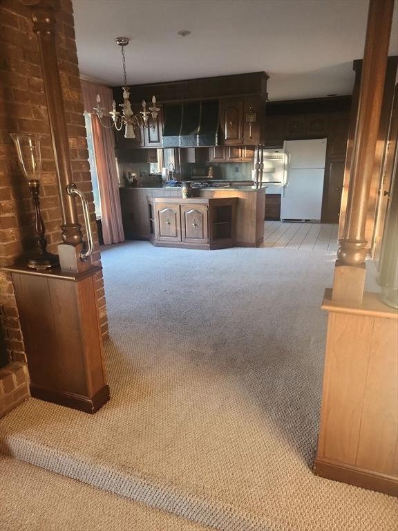 bar featuring dark brown cabinetry, white fridge, light colored carpet, and wood walls