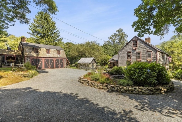 view of home's exterior with a chimney, driveway, a garage, and an outdoor structure