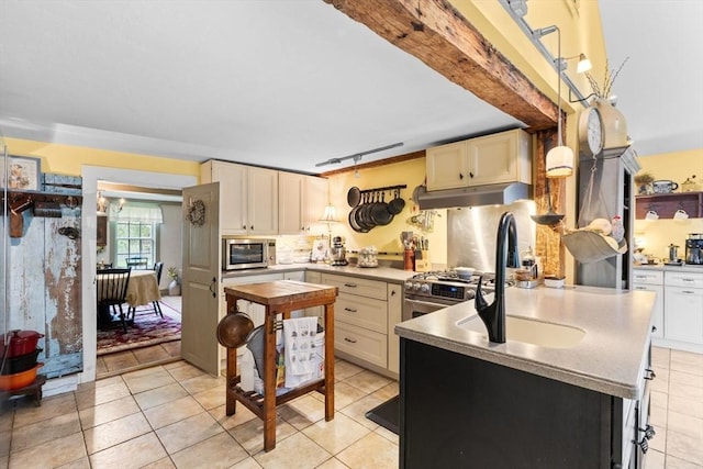 kitchen featuring appliances with stainless steel finishes, under cabinet range hood, light tile patterned flooring, a peninsula, and tasteful backsplash