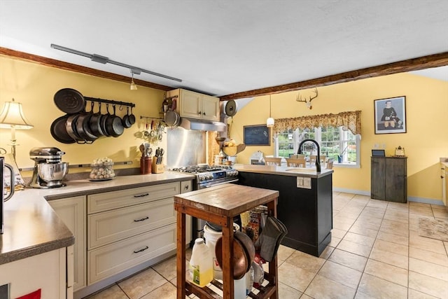 kitchen with under cabinet range hood, light tile patterned floors, a peninsula, a sink, and cream cabinets