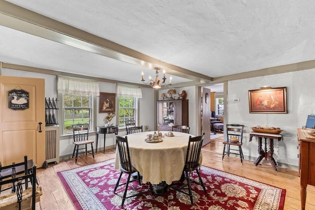 dining room featuring light wood-type flooring, a chandelier, and beamed ceiling