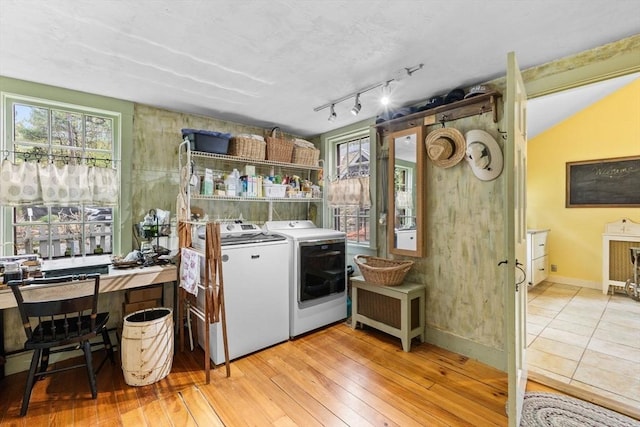 laundry area featuring washing machine and dryer, light wood-style floors, and baseboards