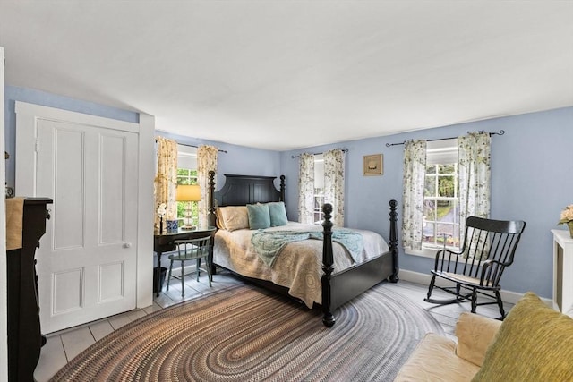 tiled bedroom featuring multiple windows and baseboards