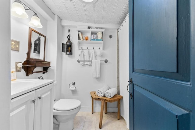 bathroom featuring an ornate ceiling, toilet, vanity, baseboards, and tile patterned flooring