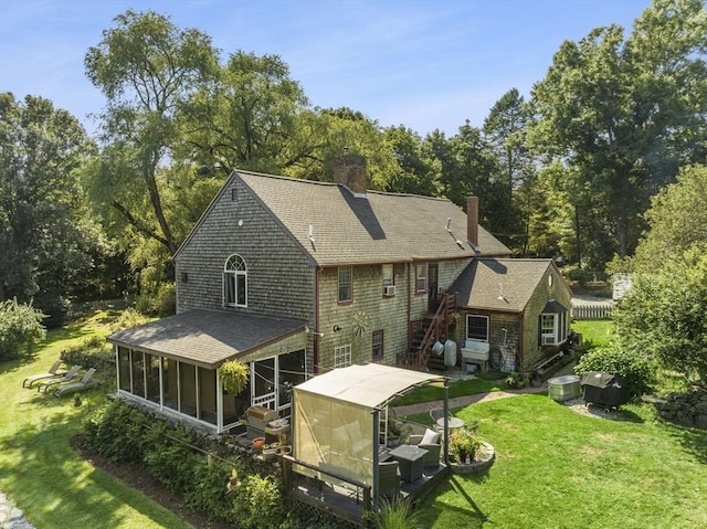 rear view of property with a sunroom, a chimney, a shingled roof, and a jacuzzi