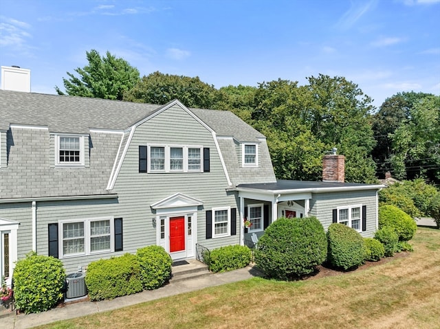 view of front of house with central AC and a front lawn