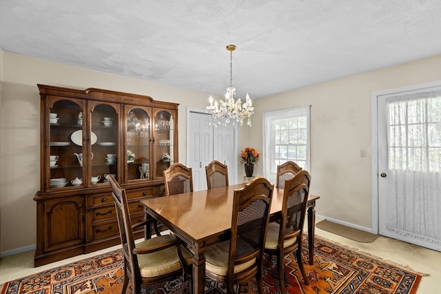 dining room featuring a chandelier, a healthy amount of sunlight, and light colored carpet