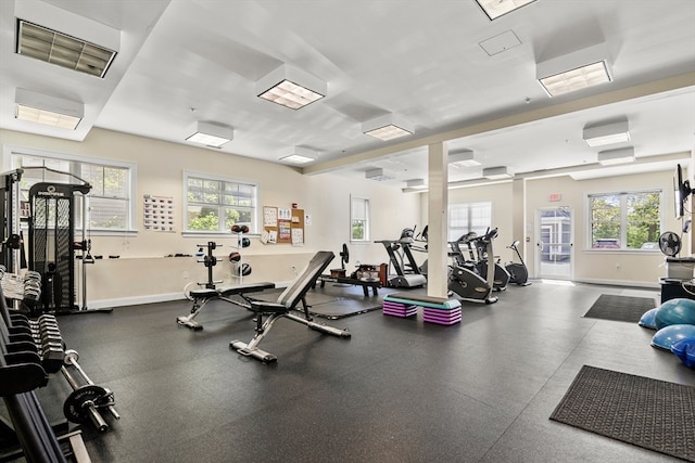 workout area with a wall mounted air conditioner and a healthy amount of sunlight