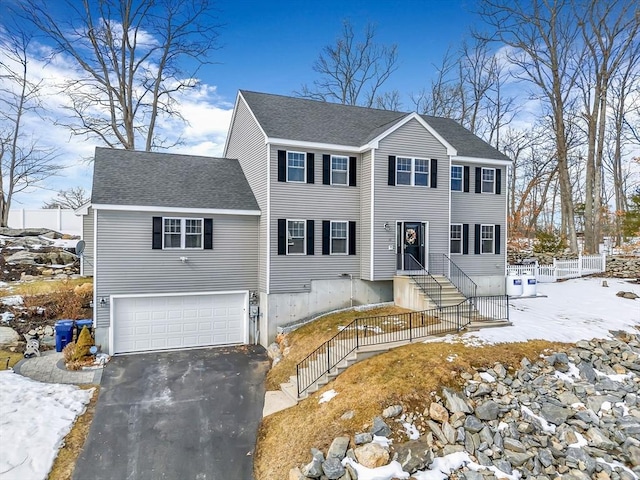 colonial inspired home featuring driveway, an attached garage, fence, and a shingled roof