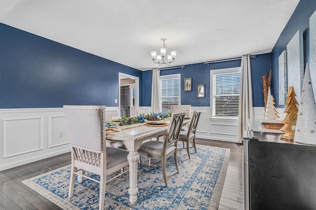 dining room featuring a chandelier, a wainscoted wall, and dark wood-type flooring