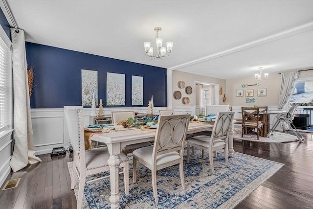 dining area featuring hardwood / wood-style floors, a wainscoted wall, a notable chandelier, and visible vents