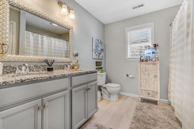 bathroom featuring visible vents, toilet, wood finished floors, baseboards, and vanity