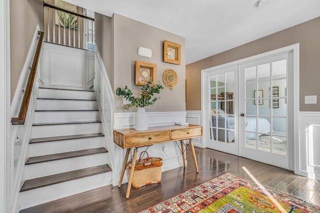 stairway featuring french doors, a decorative wall, wainscoting, and hardwood / wood-style flooring