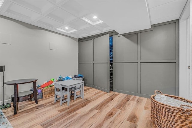 game room with a decorative wall, recessed lighting, light wood-style floors, and coffered ceiling